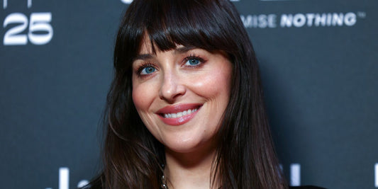 Dakota Johnson with long dark hair photographed against a neutral backdrop