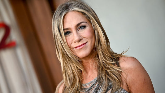 Jennifer Aniston with soft, naturally greying shoulder-length hair, smiling in natural light