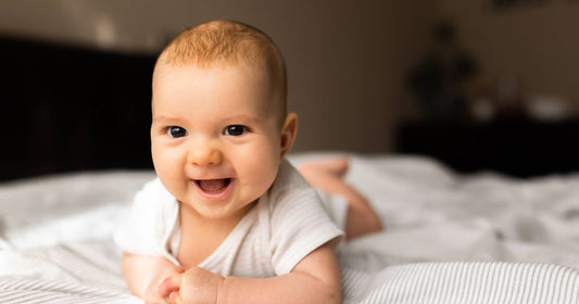 Smiling three-month-old baby lying on a blanket and playing, close-up of fine baby hair