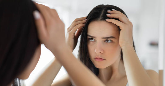 Close-up of a woman checking thinning hair at her parting in a mirror