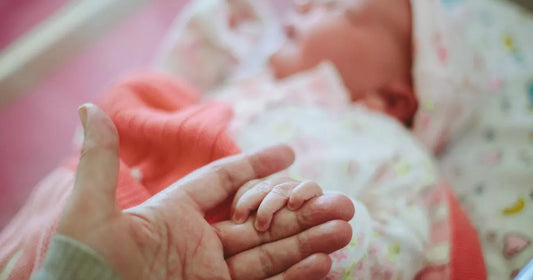 Newborn baby holding mother’s hand — early hair colour may change in infancy