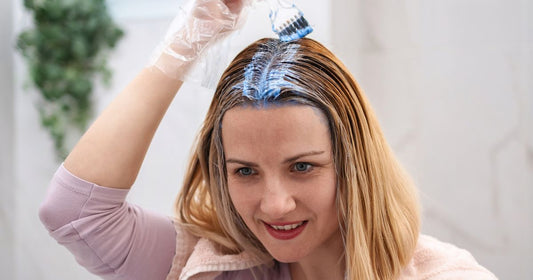 Person applying hair dye with brush in a salon
