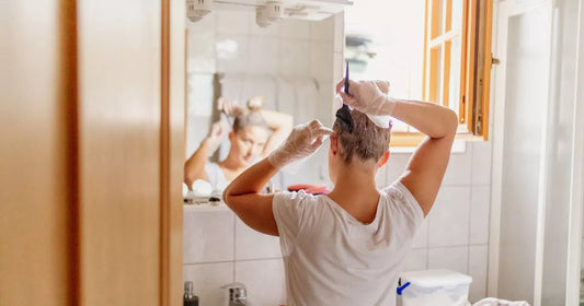 Person applying permanent hair dye at home with gloved hands