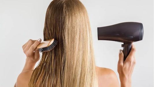 Woman drying hair with a hair dryer — dermatologists warn about daily heat damage