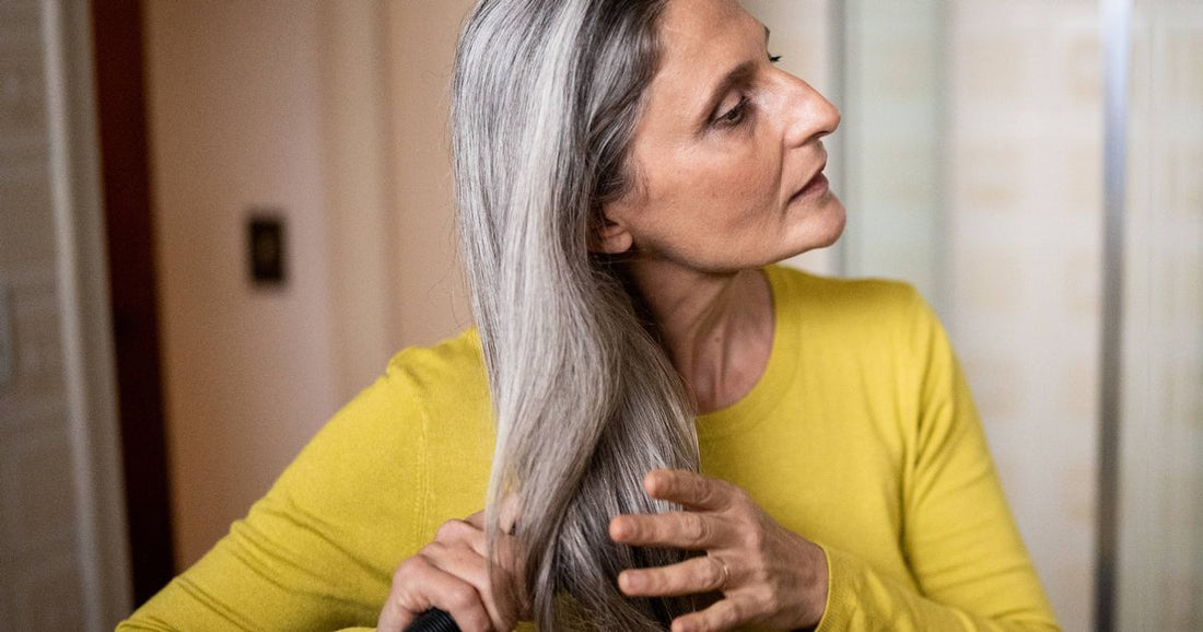 Close-up of a woman washing hair under a shower, illustrating hair-thickening shampoo use