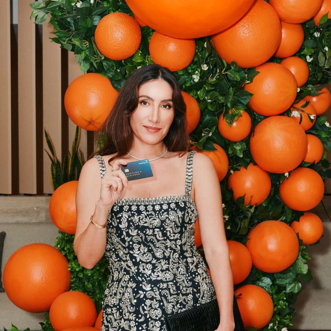 Jen Atkin smiling while styling a model’s long wavy hair in a studio
