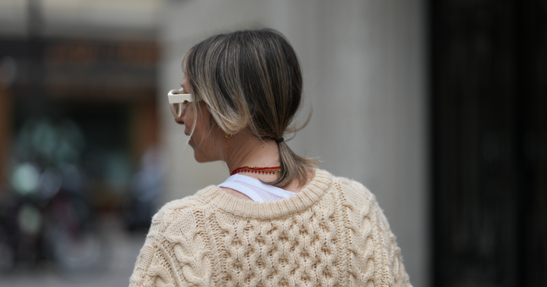 Woman brushing hair while considering iron deficiency and hair loss
