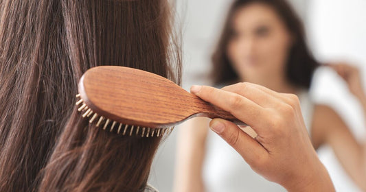 Woman looking self-conscious while examining her thinning hair in a mirror