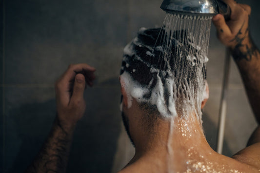 Person massaging shampoo into hair in the shower