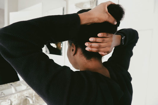 Pregnant person with long hair looking at their reflection