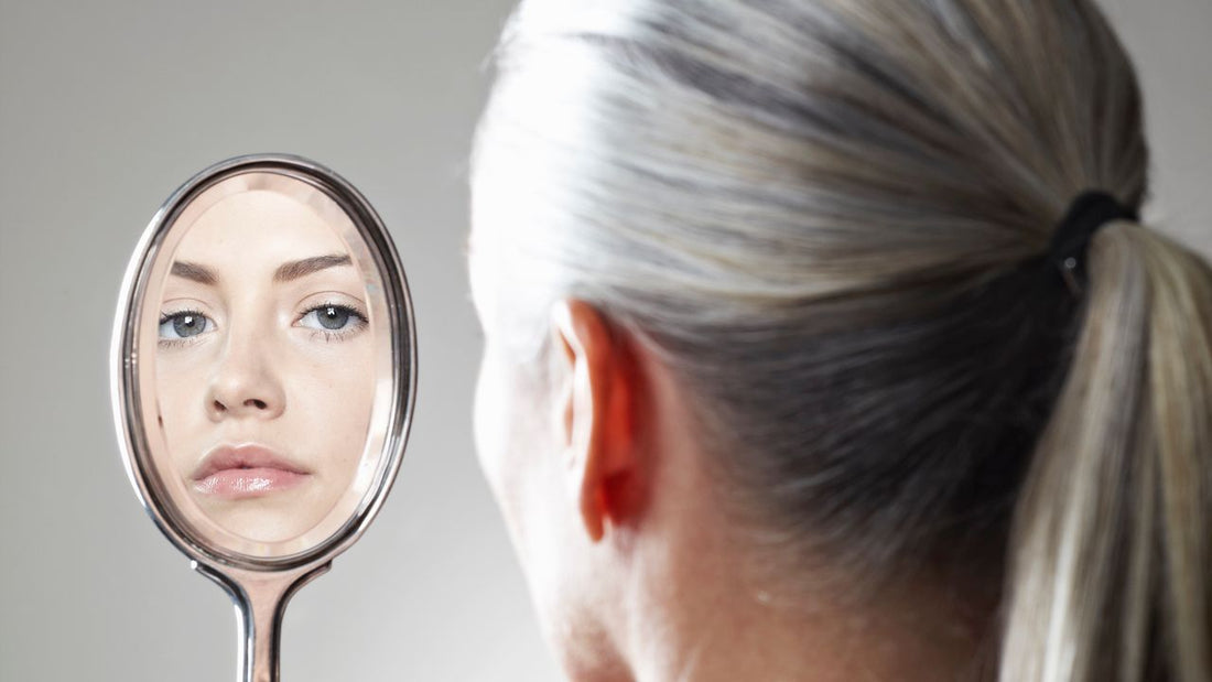 Woman examining strands of hair under natural light, suggesting early greying
