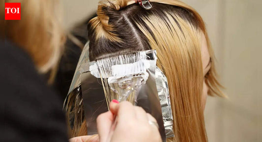 Close-up of a stylist applying dark permanent hair dye with a tint brush in a salon