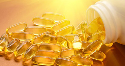 Vitamin D capsules spilling from a bottle on a neutral background
